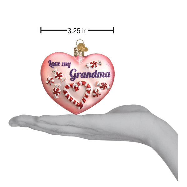 Pink heart-shaped Grandma ornament with candy cane details, shown being held for scale.