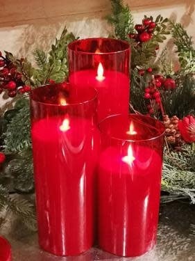 Red glass candle with realistic moving flame technology on a white background.