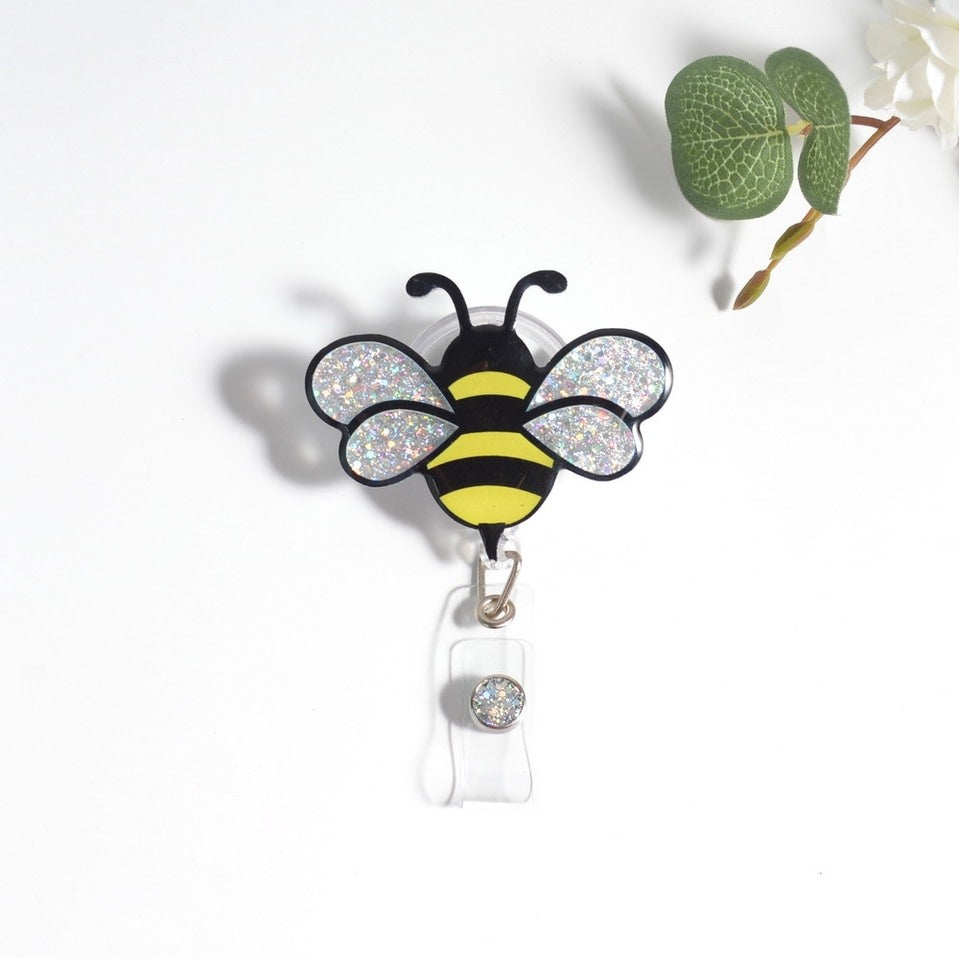 Glitterific badge reel featuring a bee silhouette with sparkly glitter resin on an alligator clip.