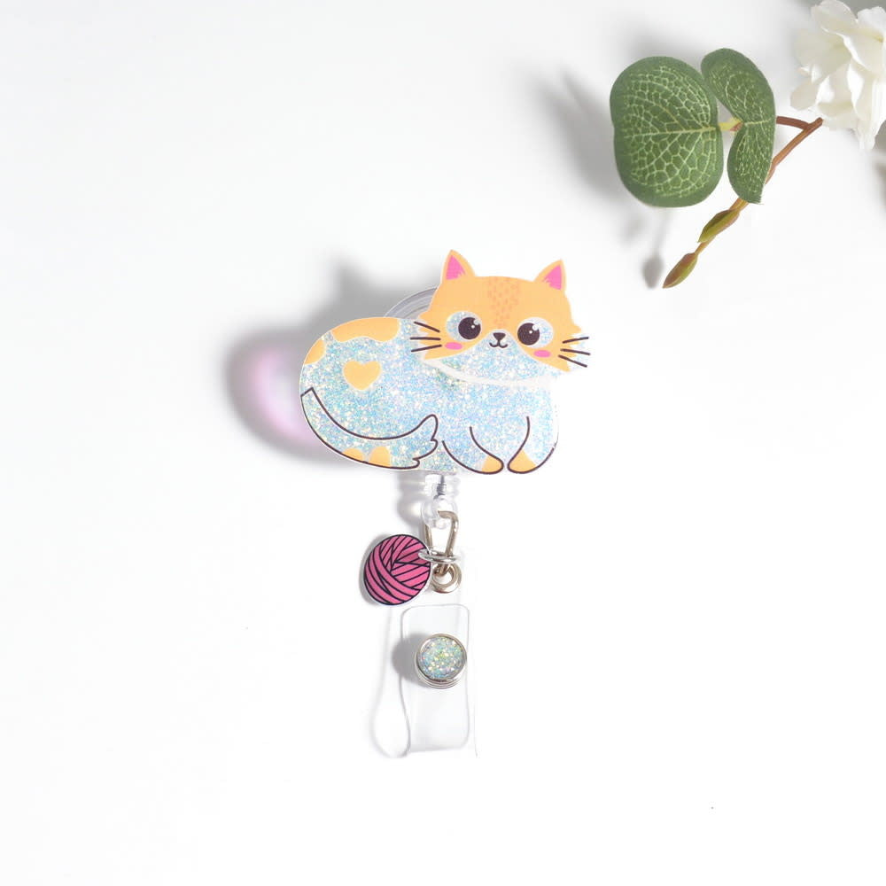 Glitterific badge reel with a black alligator clip holding a sparkly glitter resin pin featuring an adorable design.