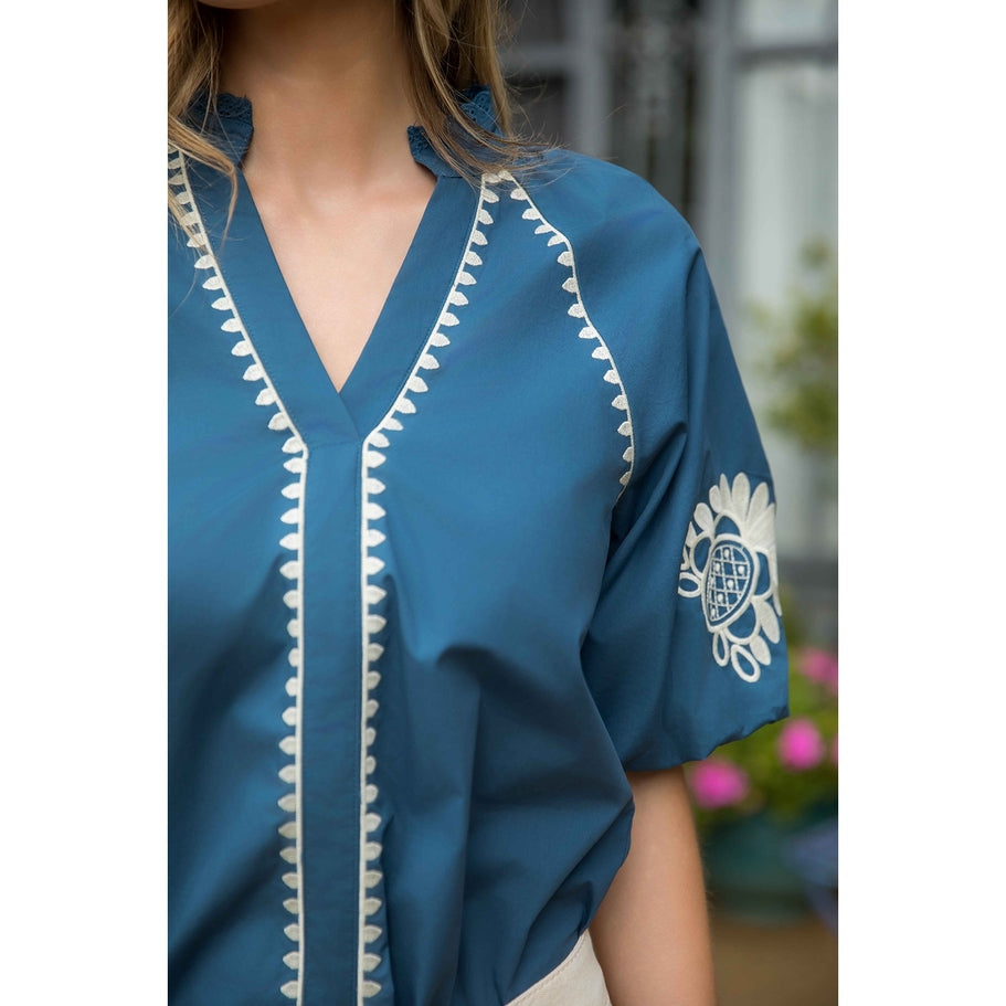Naomi embroidered cotton top with V-neckline and puff sleeves in a light neutral tone.