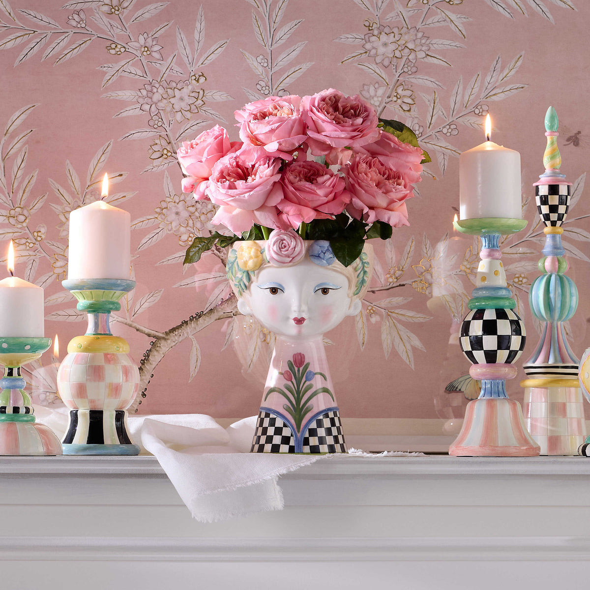 Hand-painted ceramic Rosy Meadow Tall Lady Vase with pink roses on a mantel with candlesticks.