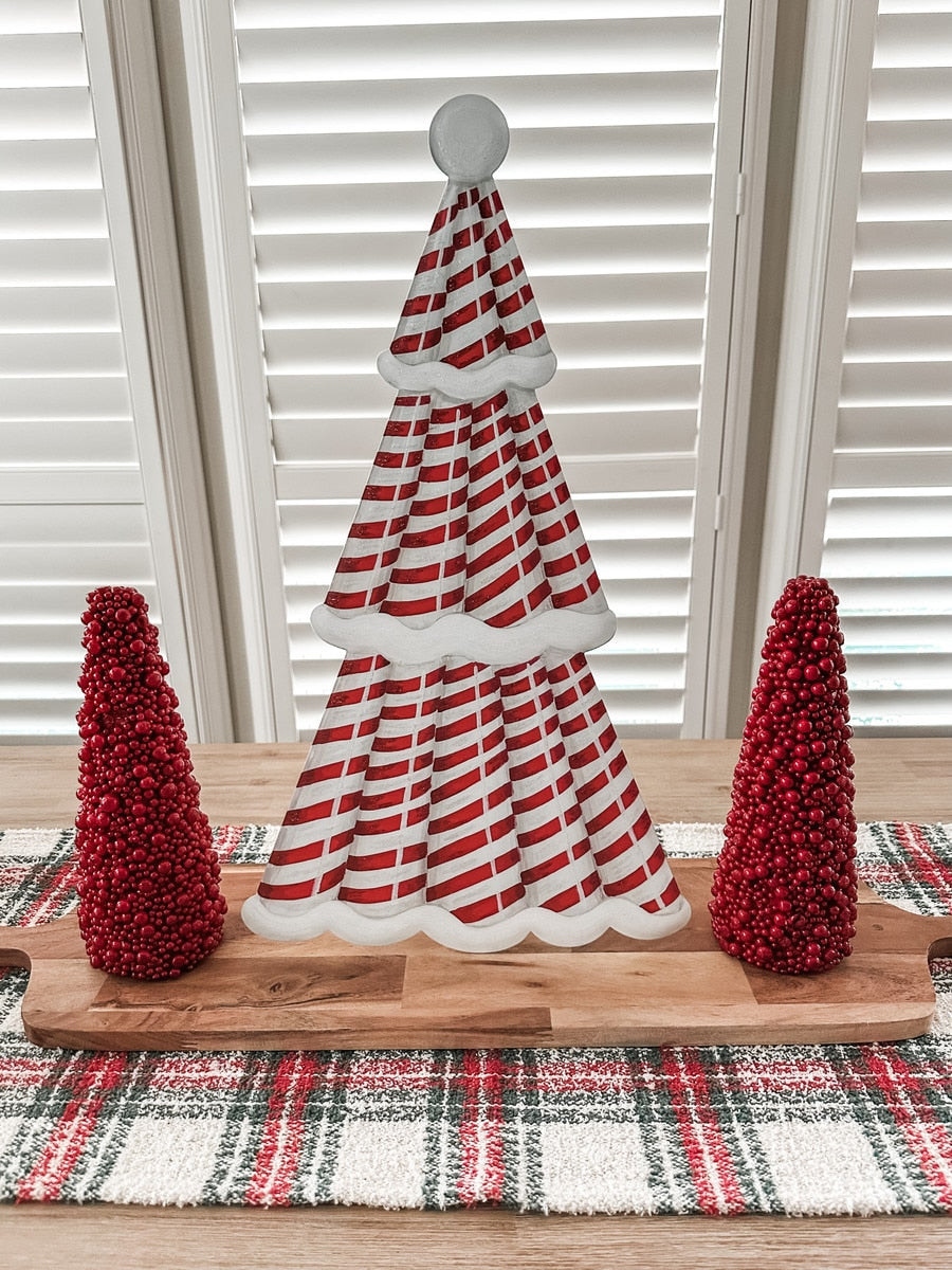 Red candy cane Christmas tree stake with white stripes on a green background.