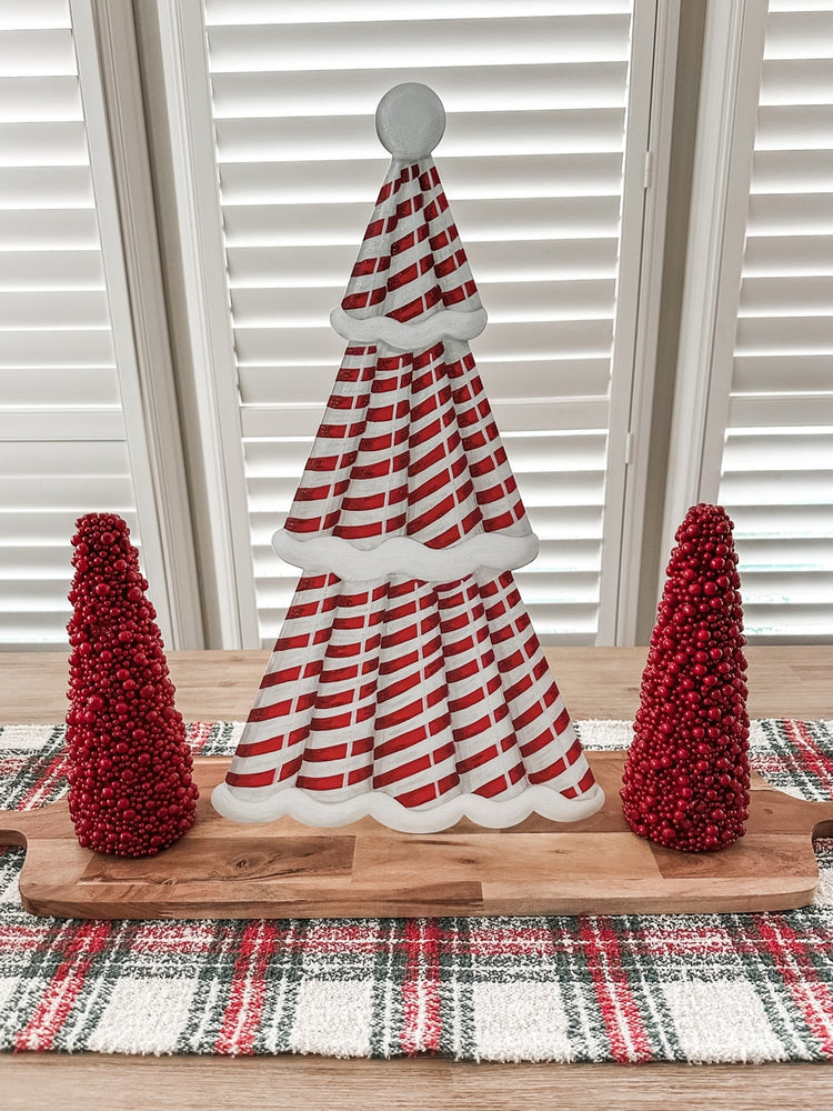 Red candy cane Christmas tree stake with white stripes on a green background.