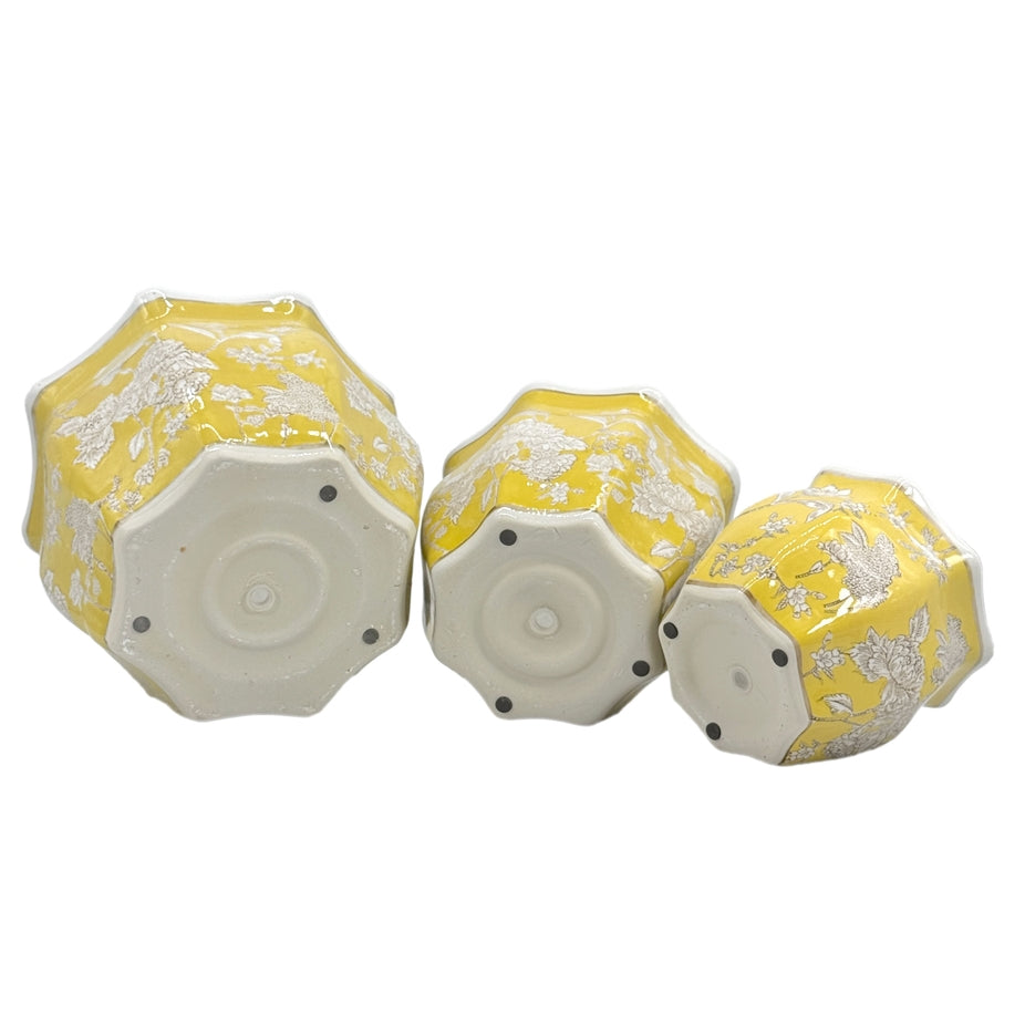 Bottom view of three yellow and white ceramic chinoiserie planter pots in small, medium, and large.