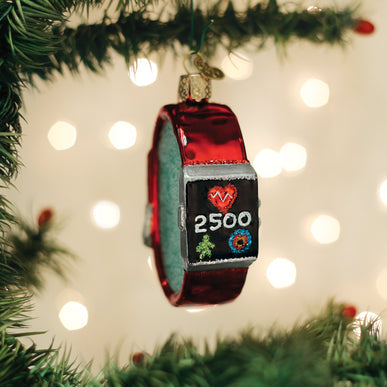 Red glass fitness watch Christmas ornament hanging on a tree, displaying a heart and step count.