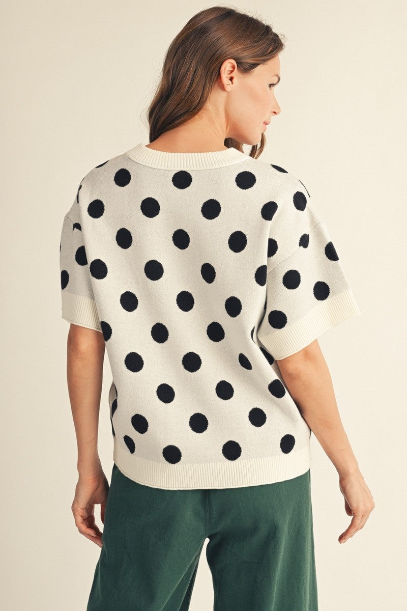 Back view of a woman wearing the Emily Polka Dot Comry Sweater Top in white with black polka dots.