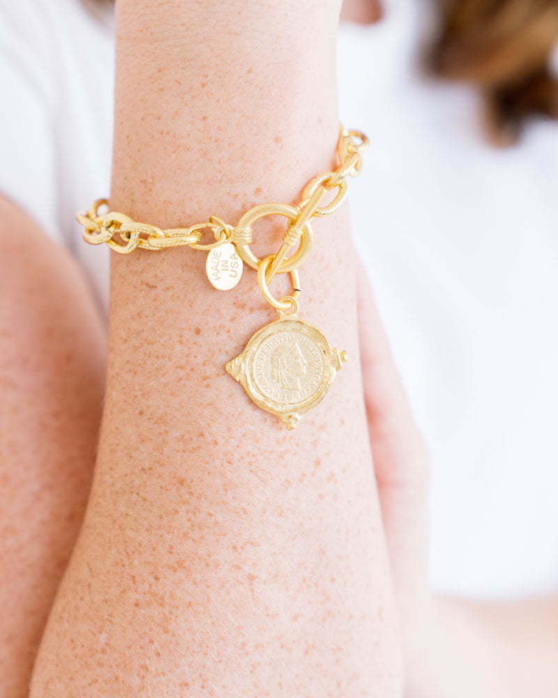Gold triple-plated bracelet featuring a Swiss franc intaglio coin on an textured chain with toggle clasp.
