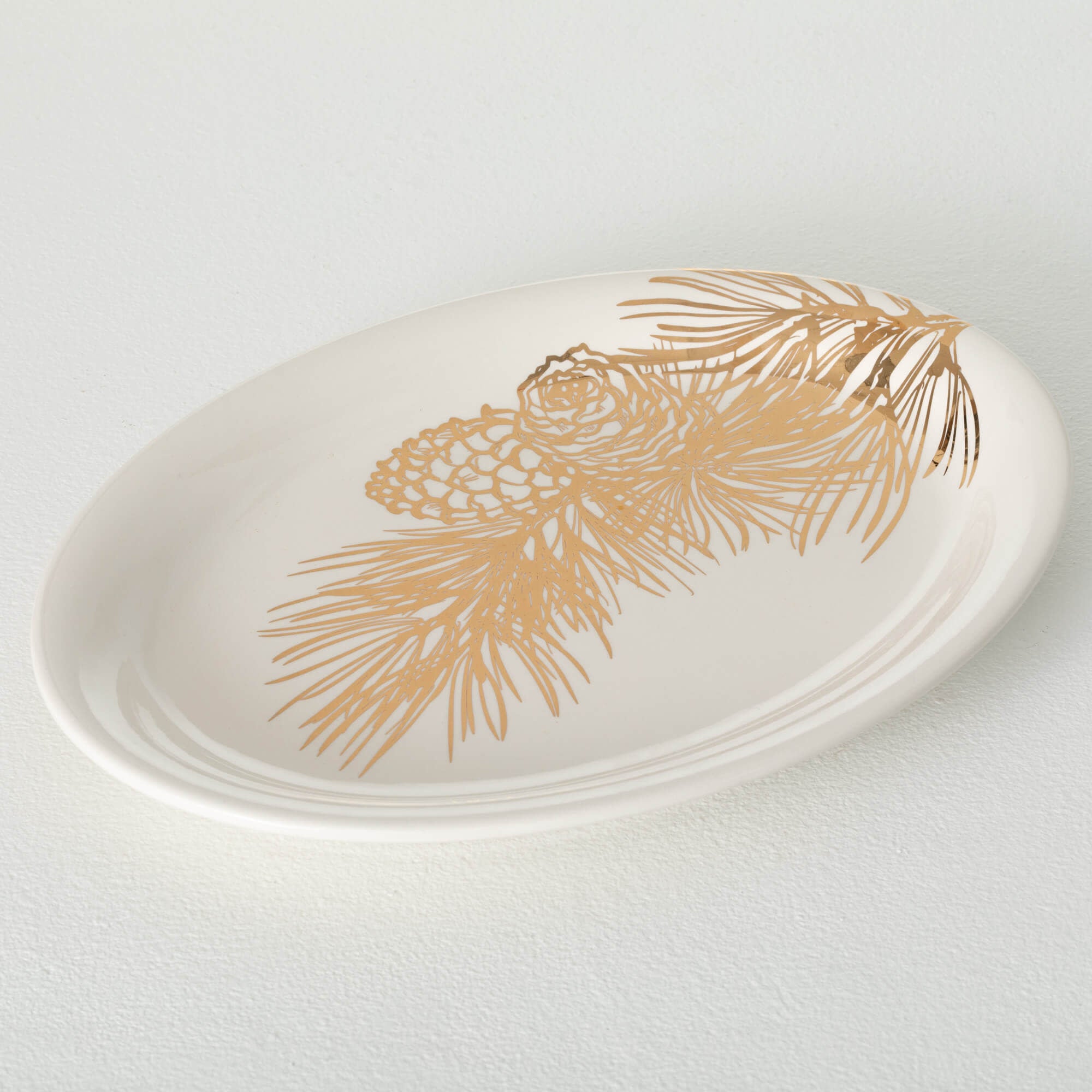 White gold ceramic platter with reflective pinecone and needle design