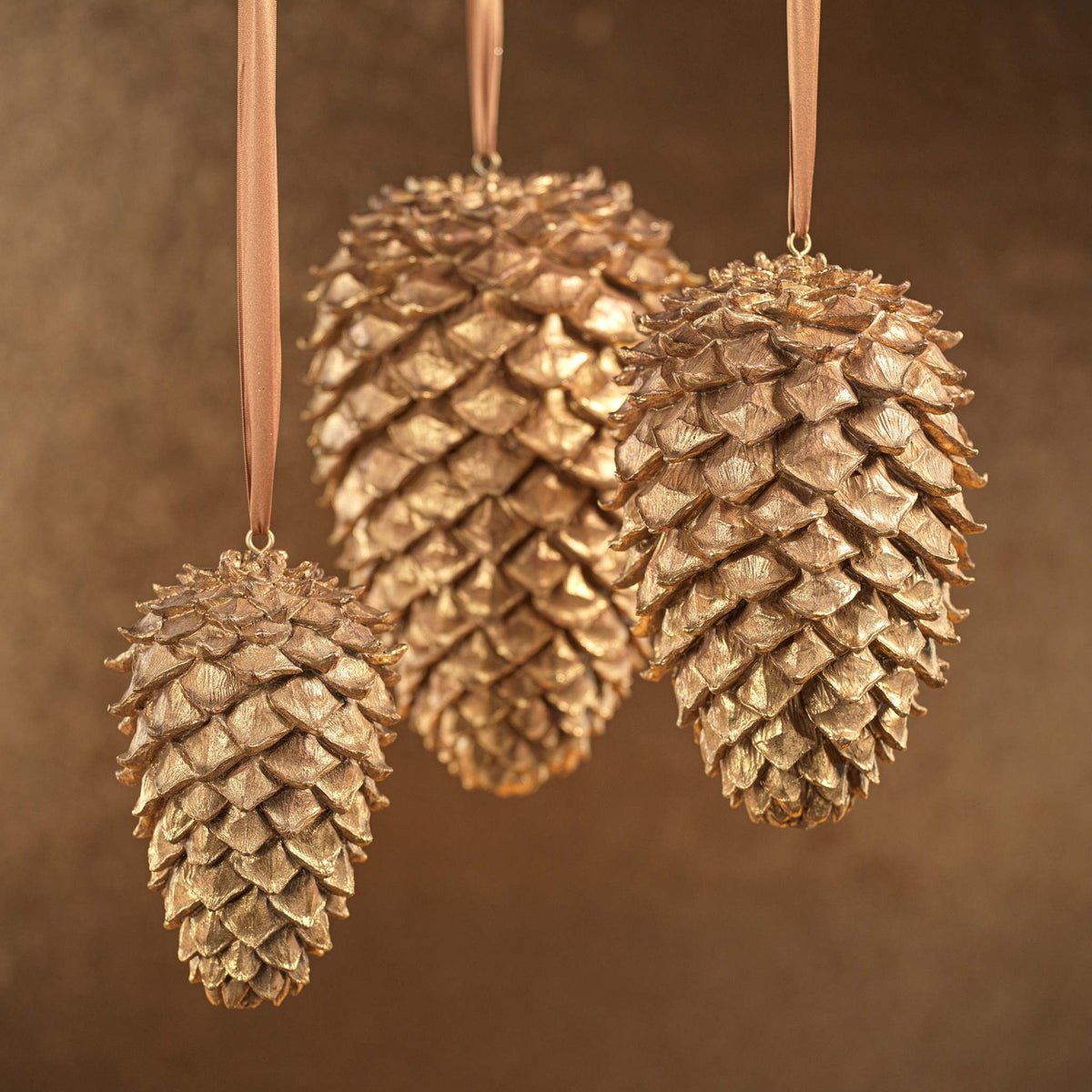 Golden polyresin decorative pine cone ornament with a realistic conical shape.
