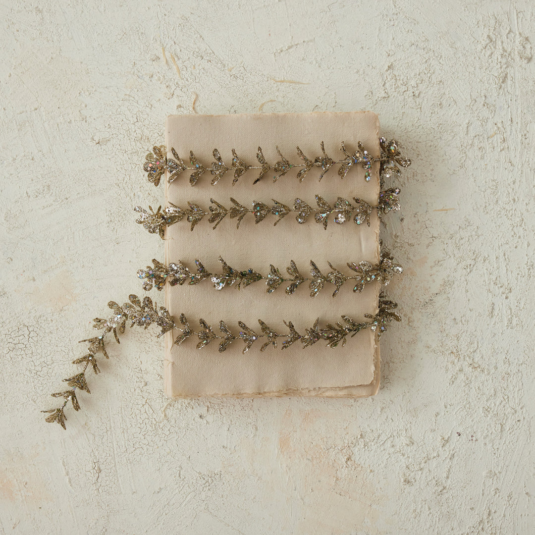 Faux boxwood garland with a champagne glitter finish wrapped around a vintage book.