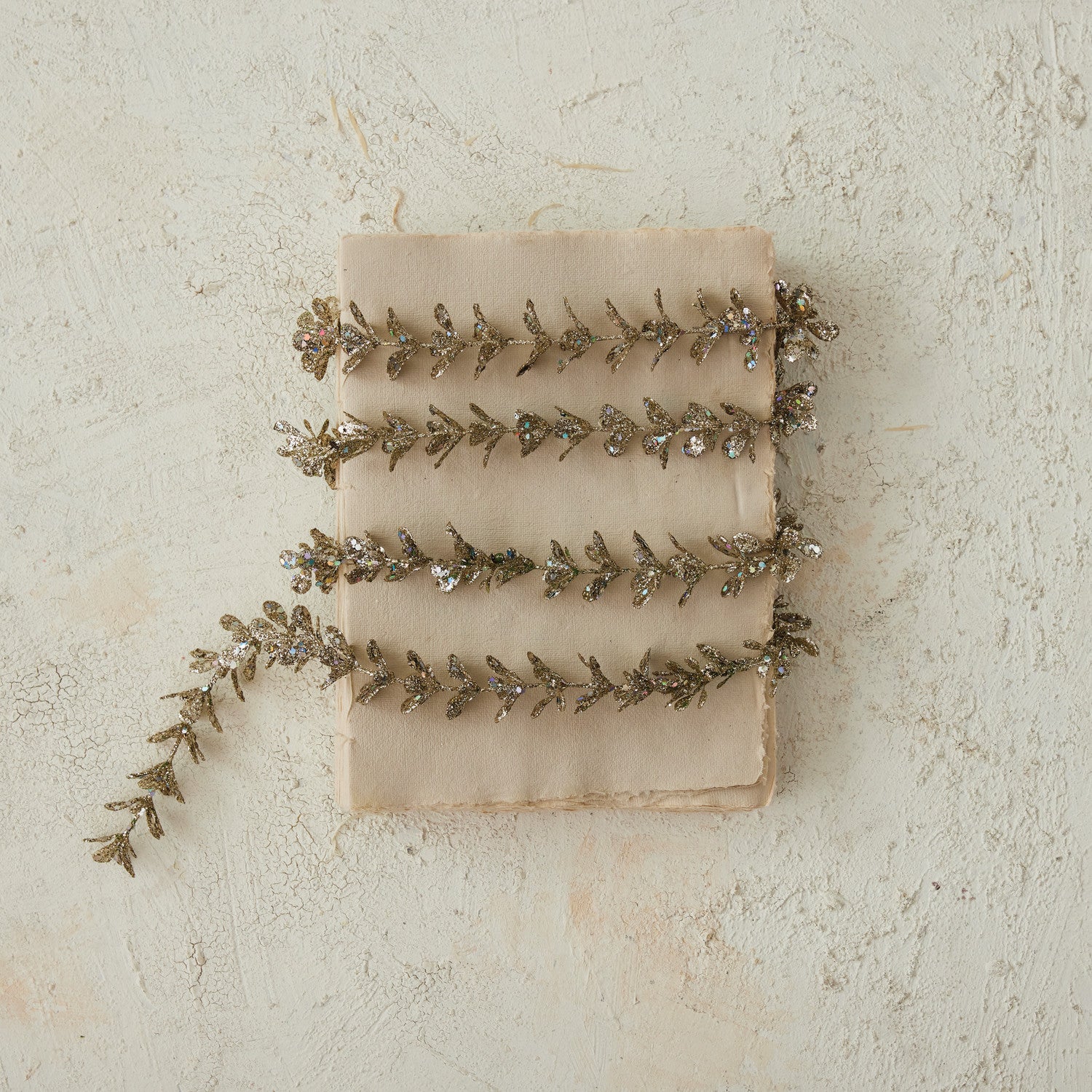 Faux boxwood garland with a champagne glitter finish wrapped around a vintage book.