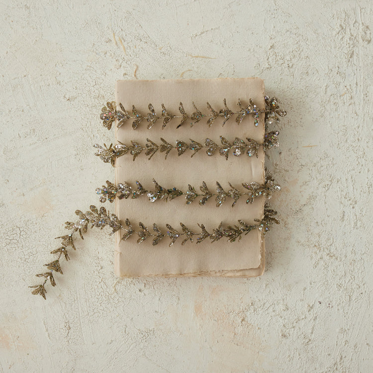 Faux boxwood garland with a champagne glitter finish wrapped around a vintage book.
