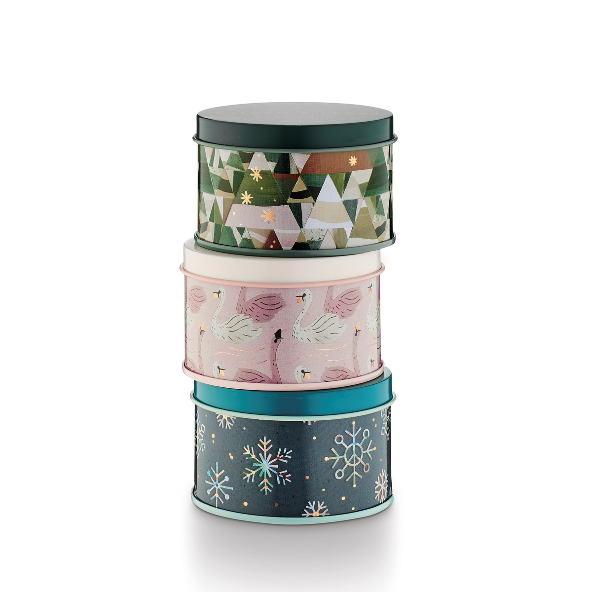 Stack of three round tin gift boxes with festive holiday designs: geometric trees, swans, and snowflakes.