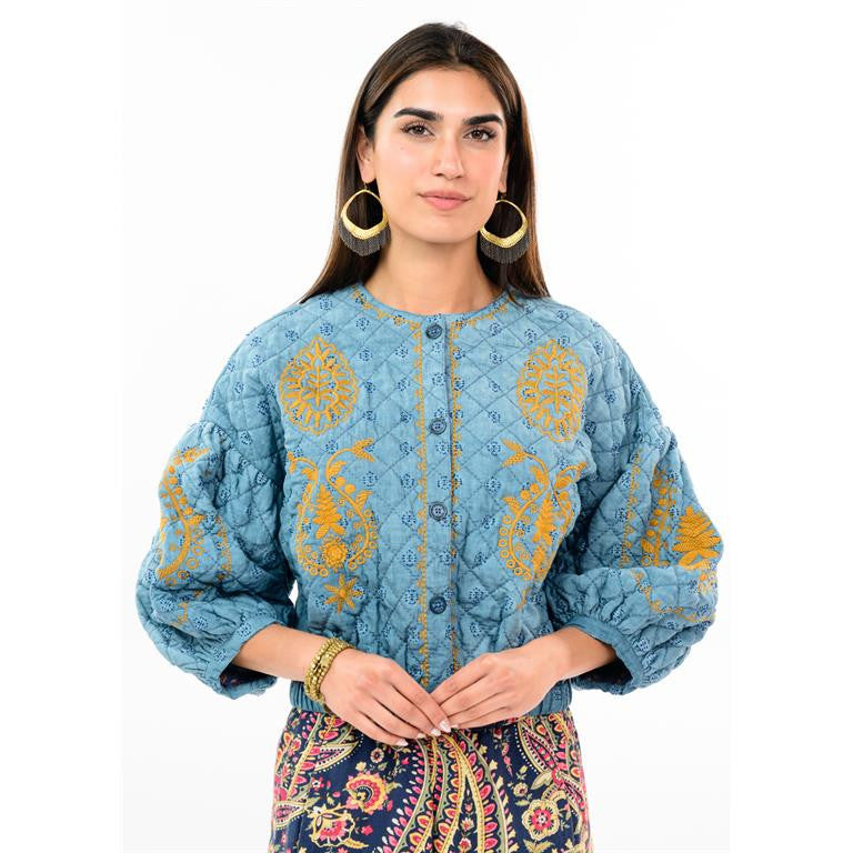 Woman wearing a Jasmin blue quilted jacket with golden floral embroidery and puff sleeves.