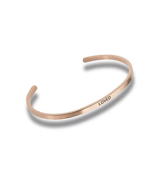 Rose gold cuff bracelet with the word LOVED engraved on the front.