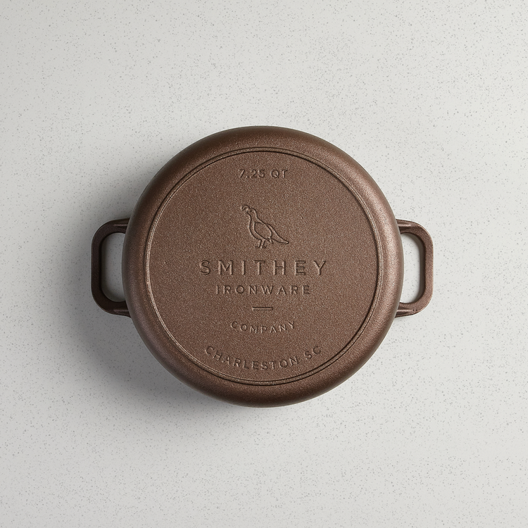 Bottom view of a 7.25 QT Smithey Ironware Dutch Oven in cast iron with engraved logo and handles.