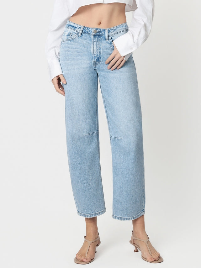 Woman wearing Kate high-rise light wash wide barrel jeans with a white cropped shirt and tan heels.