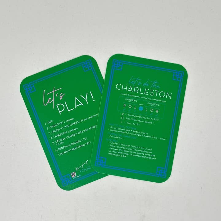 Two green plastic Mahjong tile shufflers with printed rules on all four sides.