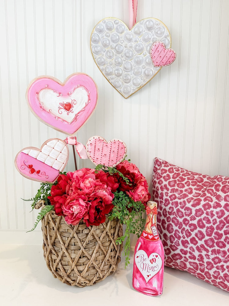 Valentine's Day display with heart-shaped cookies, pink flowers, and a champagne bottle decoration.