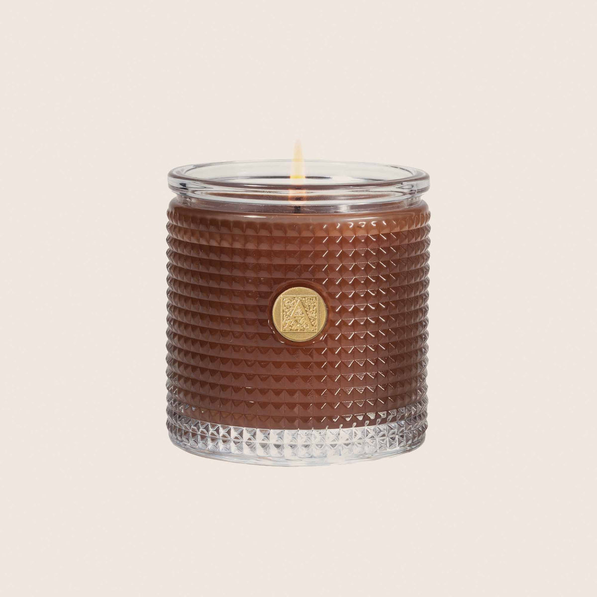 6 oz cinnamon cider scented candle in rich caramel brown wax inside a textured glass cylinder with medallion.