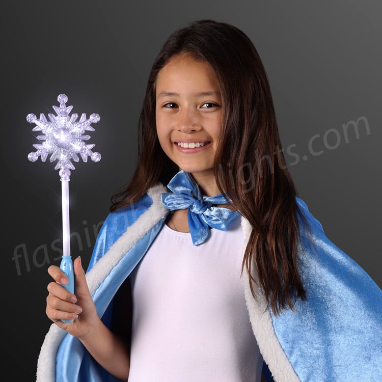 A girl in a blue cape holding a glowing Blinky Light Up Snowflake Wand with white LED lights.