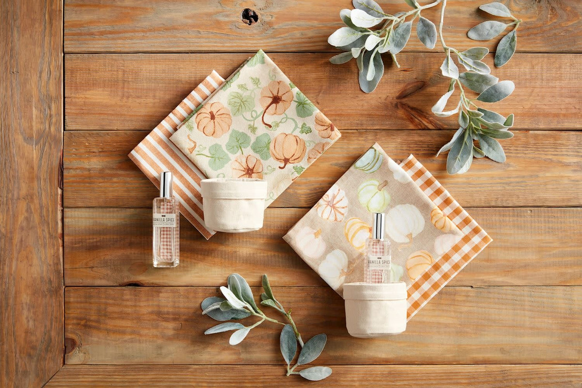 Canvas bucket holding two cotton hand towels and a glass bottle Vanilla Spice room spray.