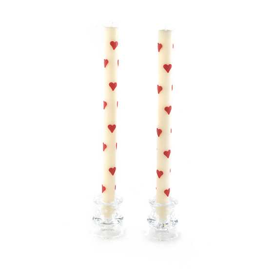Set of two tall, cream-colored taper candles decorated with small red hearts in glass holders.