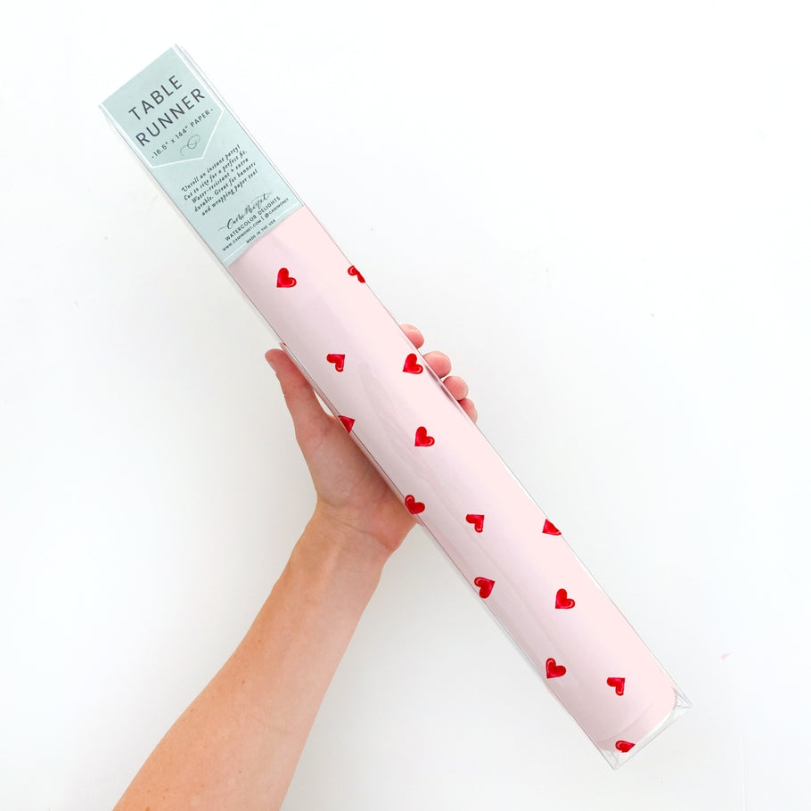 White matte paper table runner with a subtle sheen featuring a ditsy pattern of small hearts.