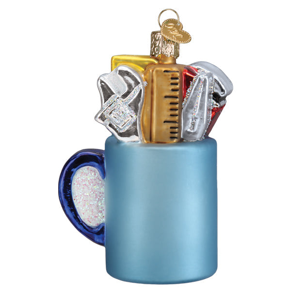 Glass Christmas ornament of a light blue mug filled with tools like a ruler and wrench.