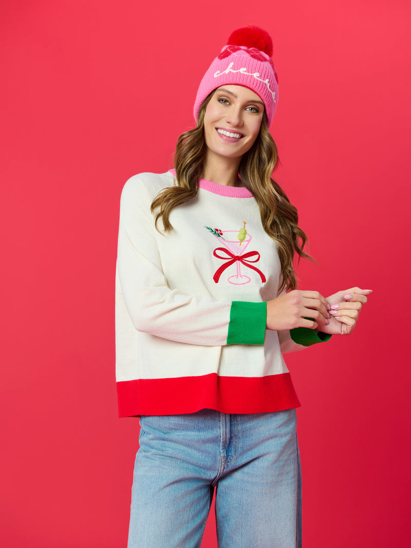 Woman in a white Martini Lightweight Boxy Sweater with red trim and a pink beanie.