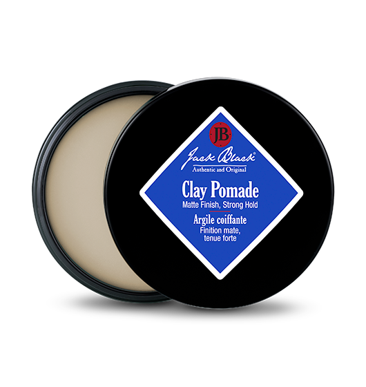 Jack Black Clay Pomade in a black tin with a blue diamond label, showing the matte product inside.