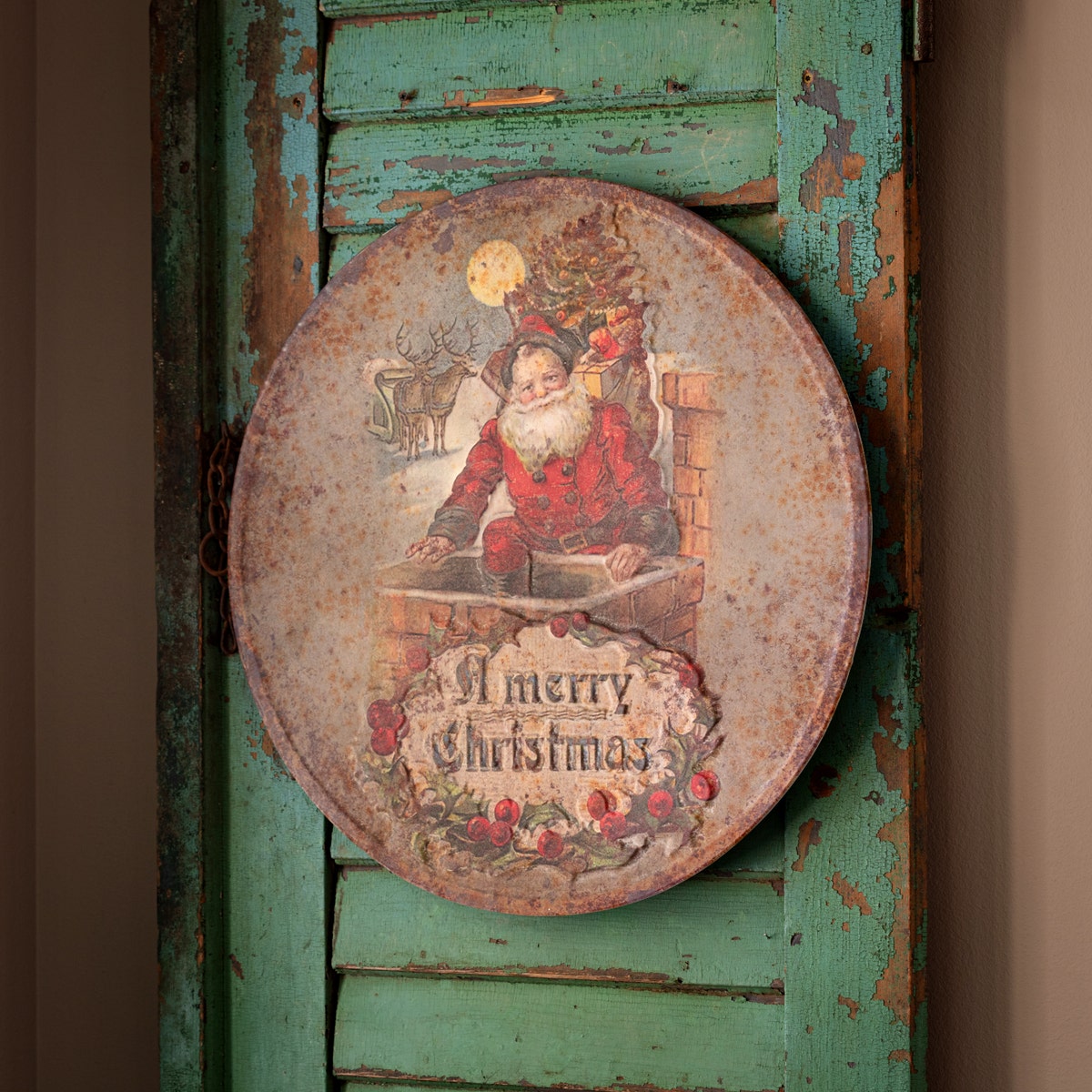 Round embossed metal sign with a red Santa Claus silhouette against a festive background.