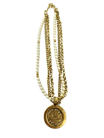 Layered pearl and gold chain necklace featuring a round coin medallion with Paris text.