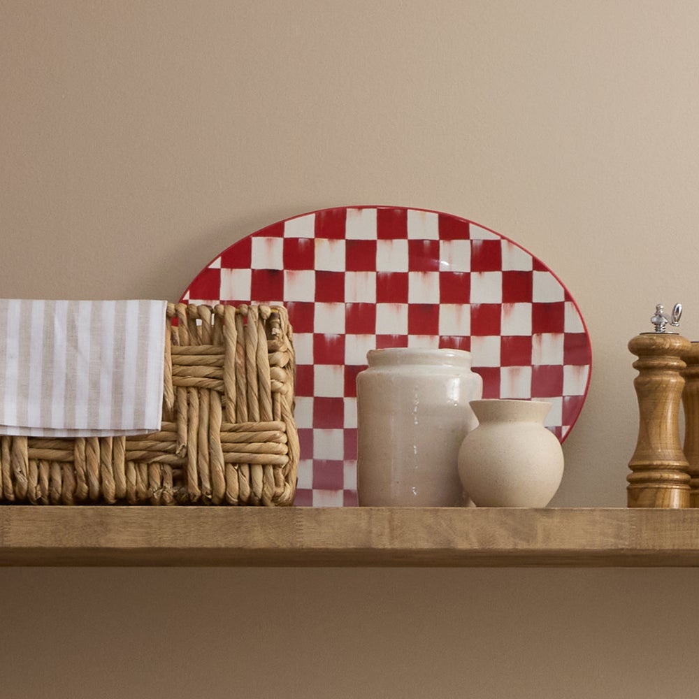 Cherry Check Serving Platter on a wooden shelf with a woven basket and ceramic jars.