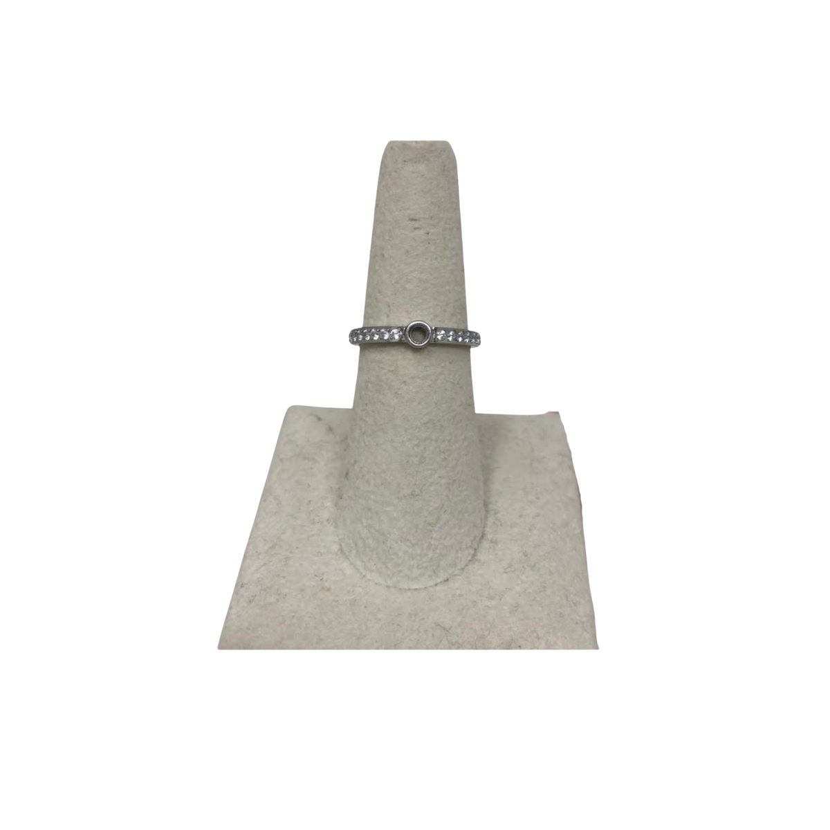 Silver eternity base ring with a central circular setting and clear stones on a display stand.
