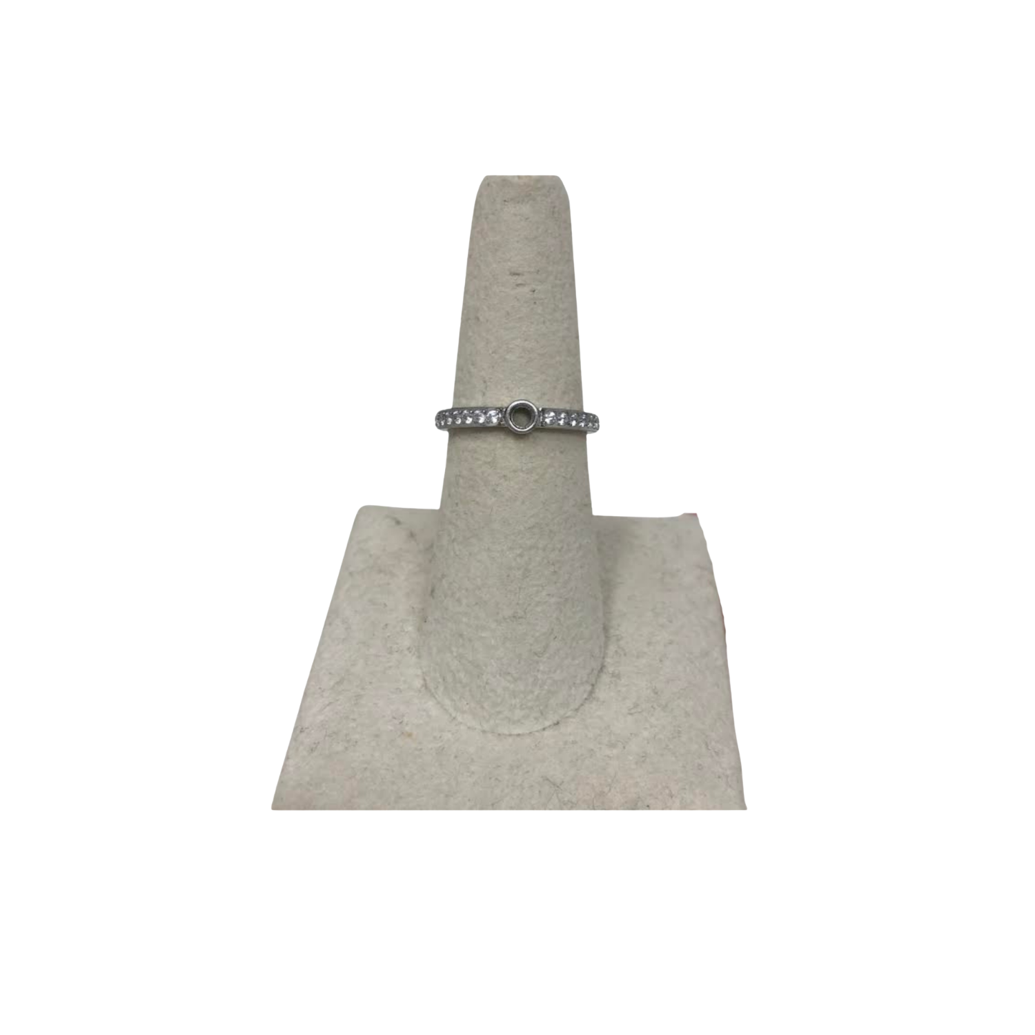 Silver eternity base ring with a central circular setting and clear stones on a display stand.