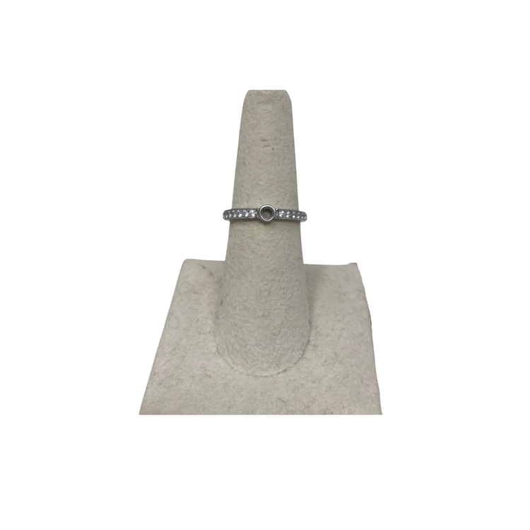 Silver eternity base ring with a central circular setting and clear stones on a display stand.