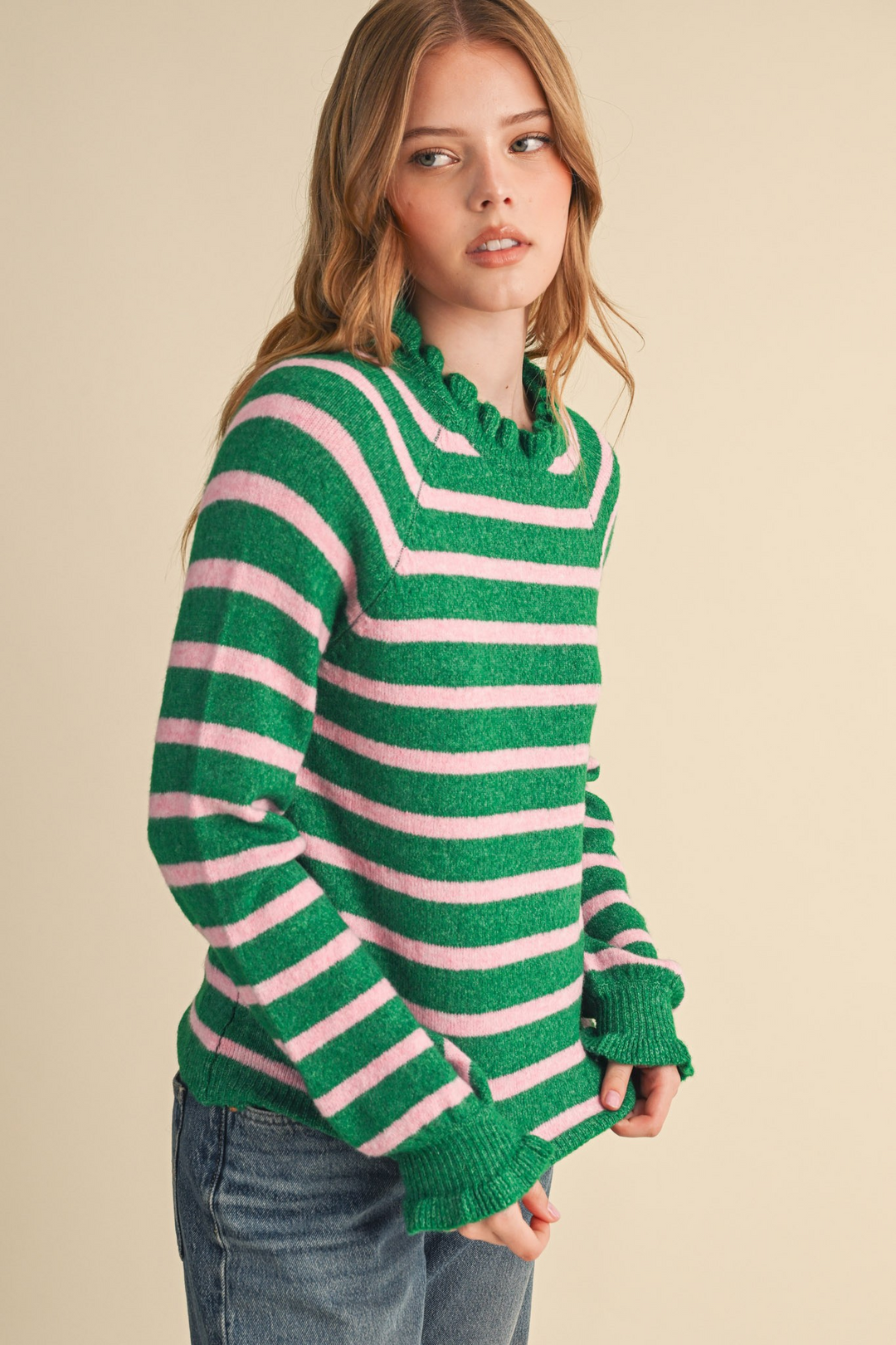 Woman wearing a green and pink striped sweater with ruffled neckline and cuffs.