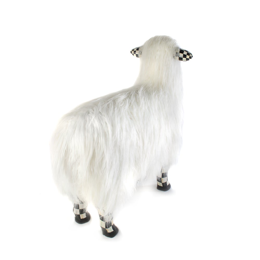 Large white sheep figurine with long faux fur and black and white checkered ears and legs.
