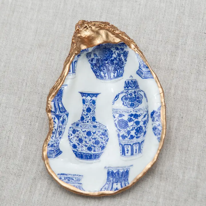 Decoupaged oyster shell with blue and white ginger jar patterns and a metallic gold rim.