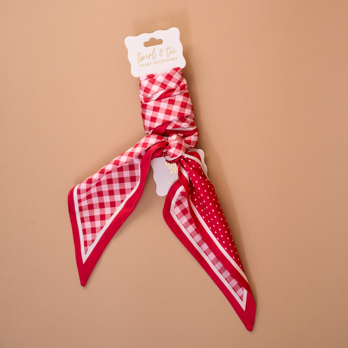 Red and white gingham and polka dot satin Twirl & Tie Scarf Accessory on a display card.