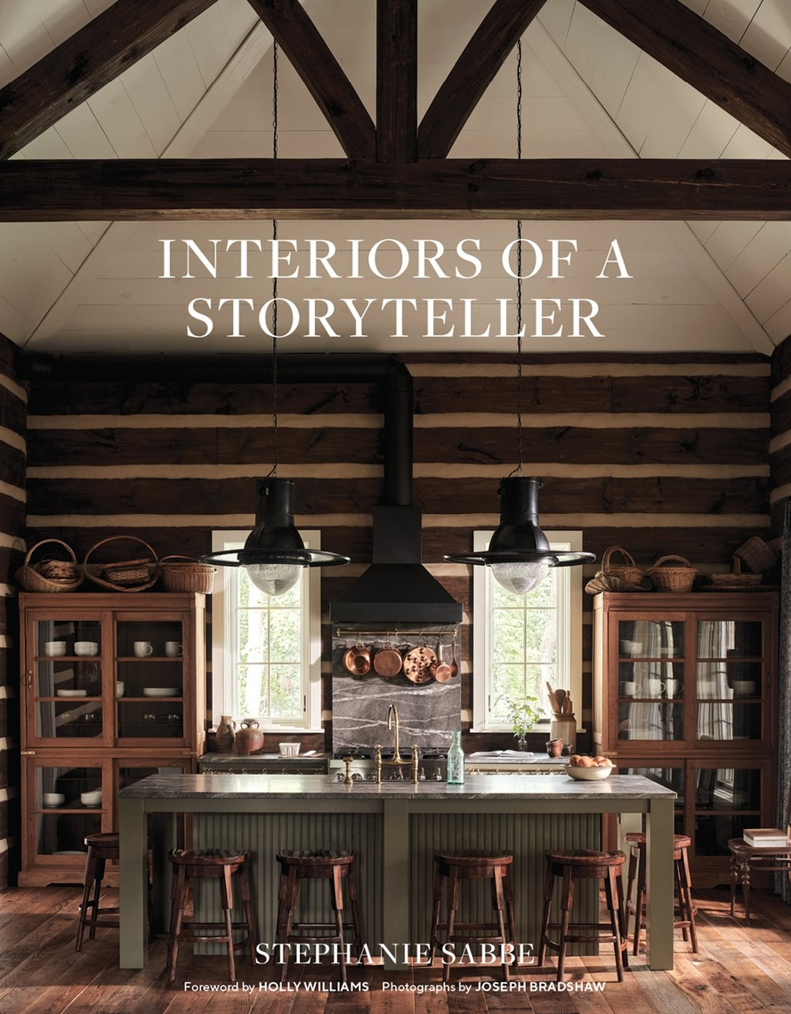 Book cover of Interiors of a Storyteller by Stephanie Sabbe featuring a rustic log cabin kitchen.