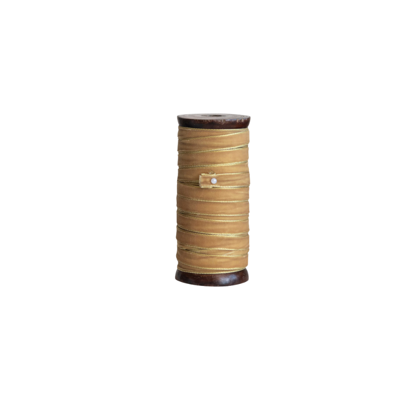 Gold velvet ribbon with metallic edges wrapped around a dark wood spool, secured with a white pin.