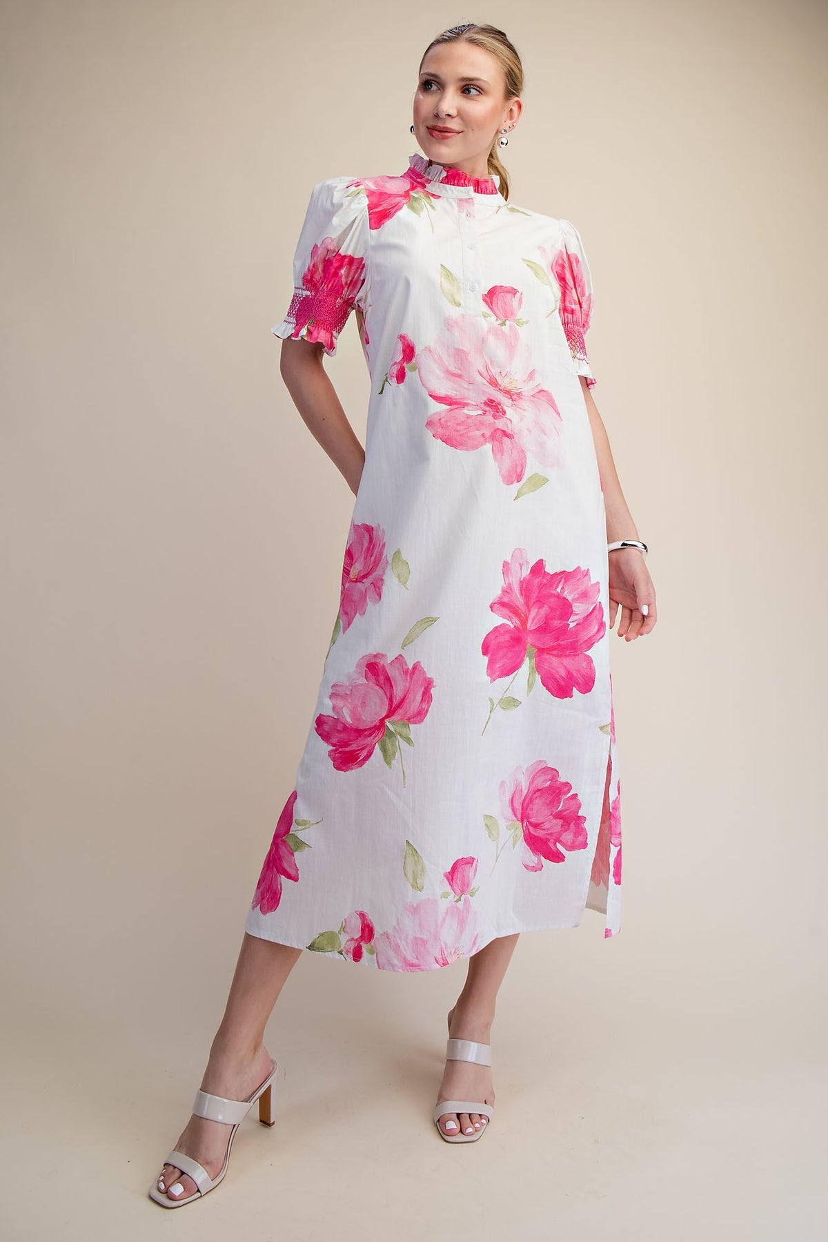 Woman in a white midi dress with pink floral print, ruffle neck, and puff sleeves.