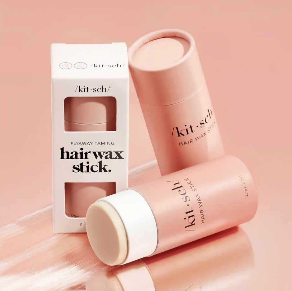 Solid vegan hair wax stick with a sleek cylindrical shape in natural beige tone.