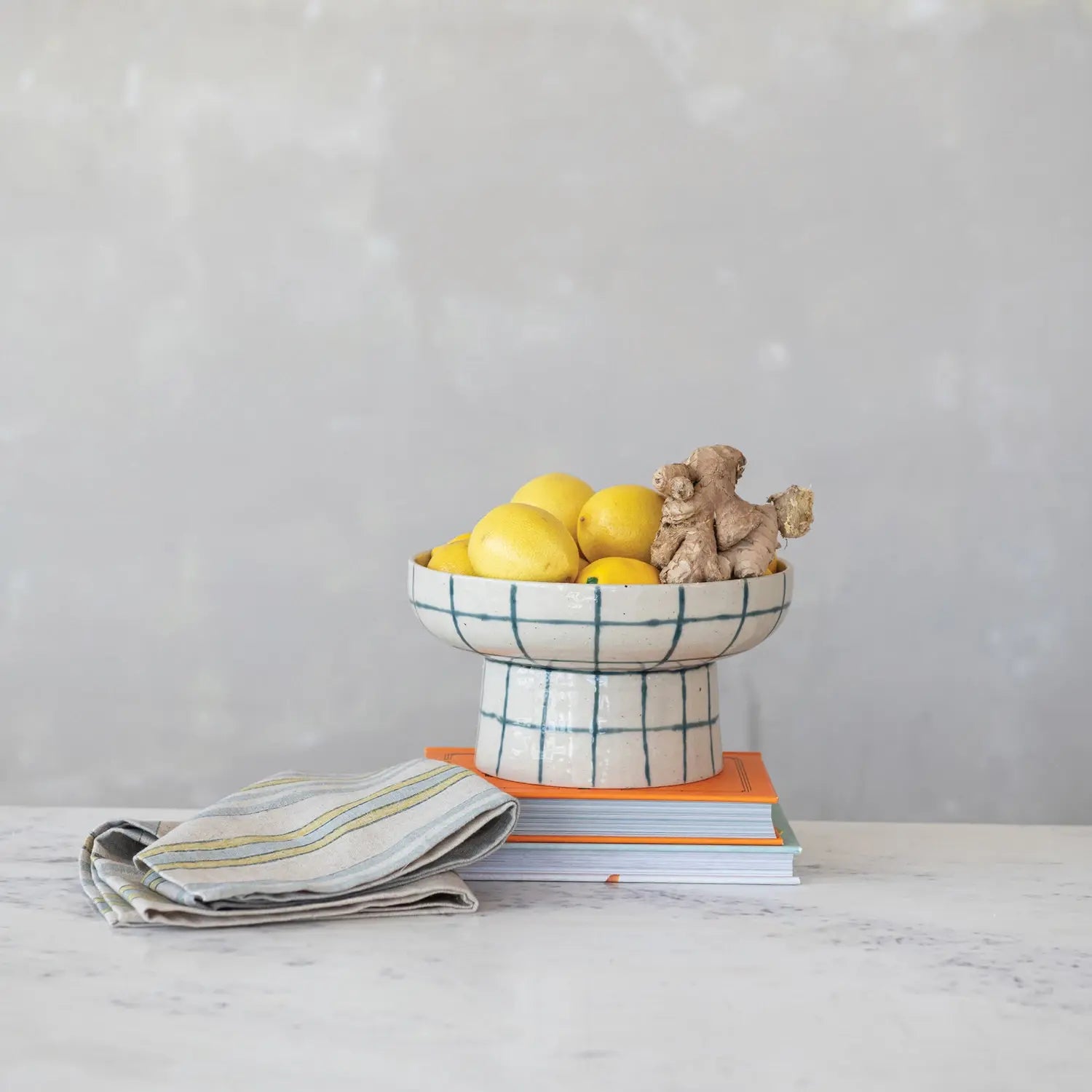 Hand-painted stoneware pedestal bowl with a round shape and cube base in earthy tones.