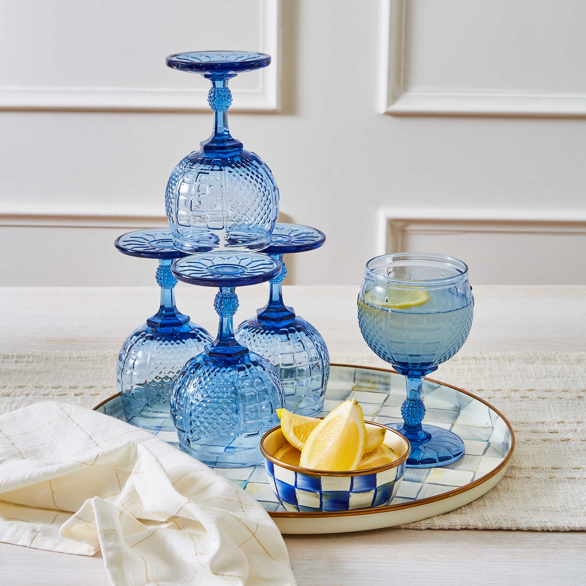 Royal Check Pinch Bowl with lemon wedges on a tray next to blue patterned glassware.
