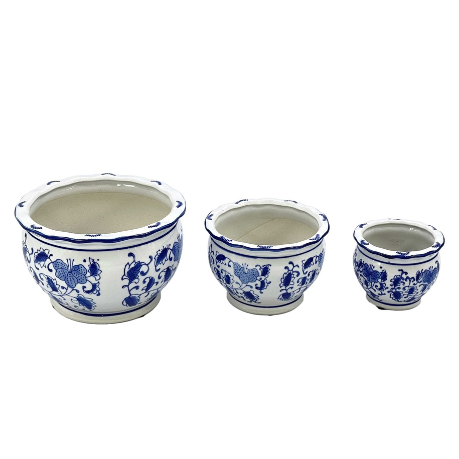 Set of three blue and white round ceramic floral pots with ruffled lips in varying sizes.