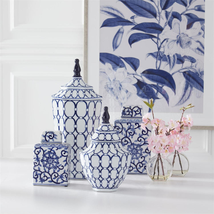 Blue and white porcelain lidded containers with oval and floral prints on a white surface.